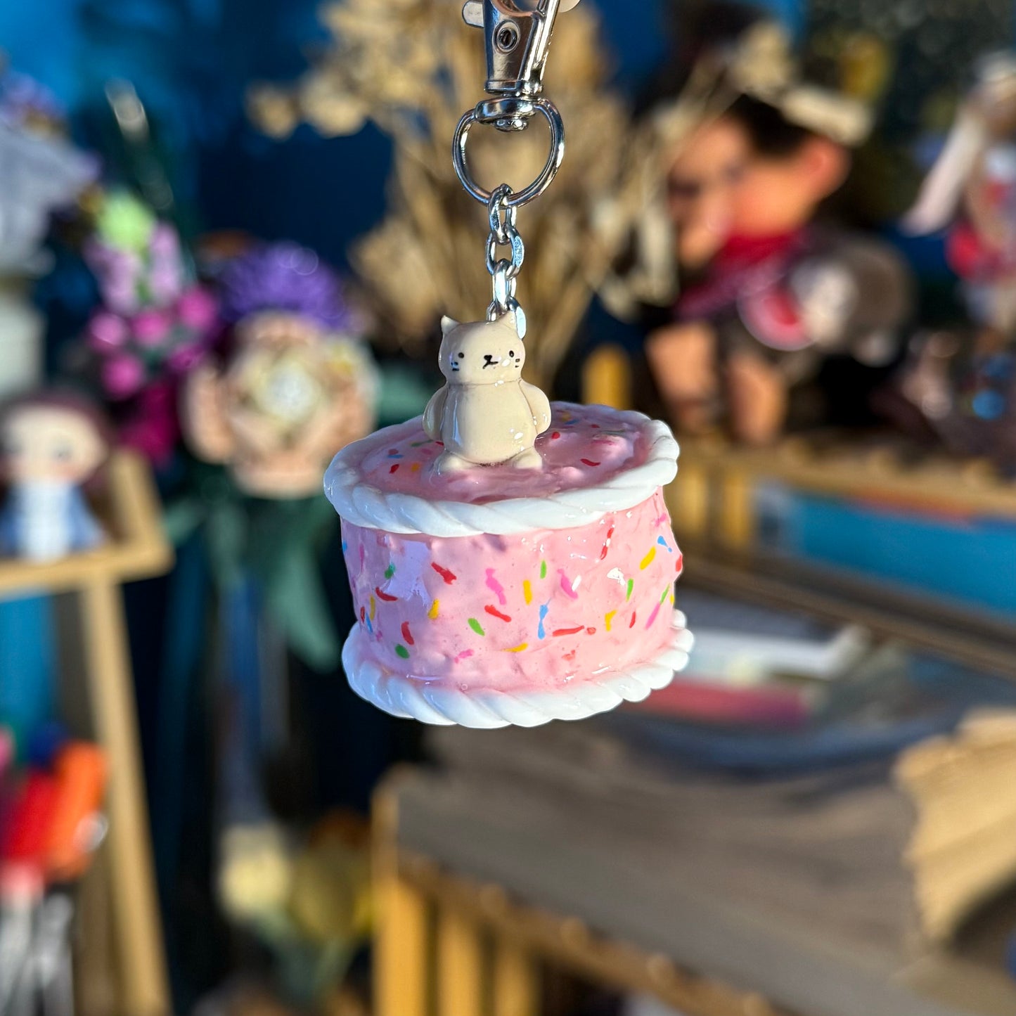 cute pink sprinkle birthday cake keychain with a cat figure on top