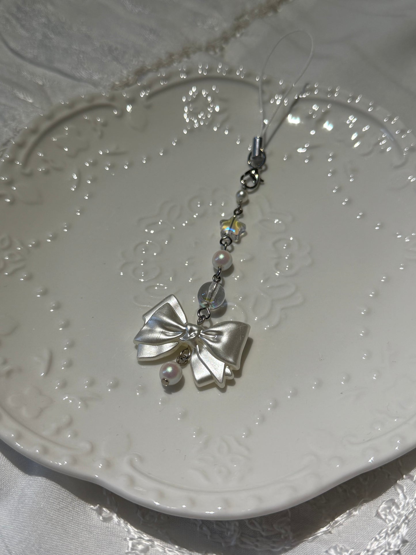 Silver bow-shaped decorative item on a textured white surface