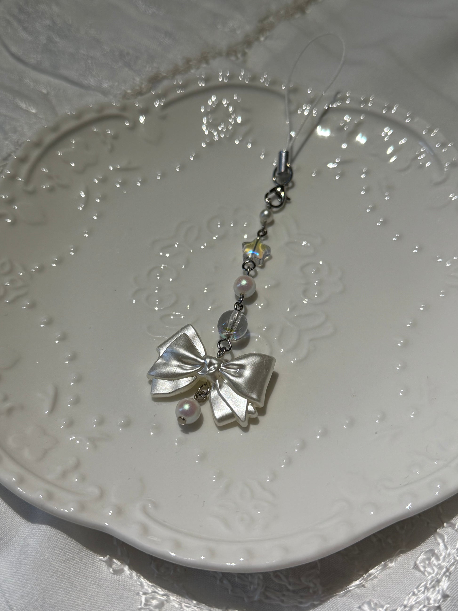 Silver bow-shaped decorative item on a textured white surface